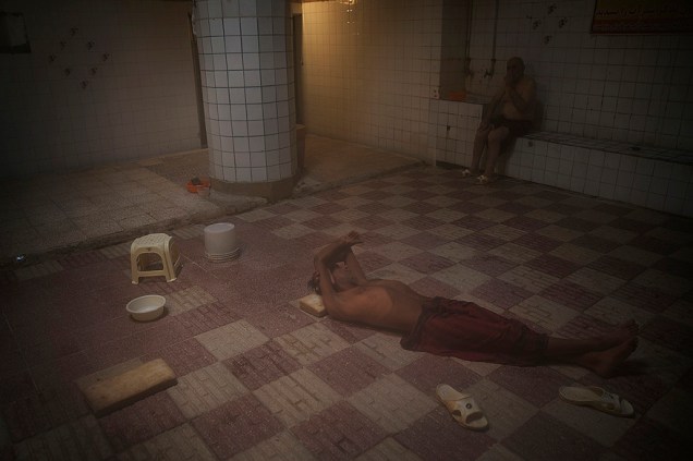 Homem descansa em uma casa de banho na cidade de Qom, no Irã
