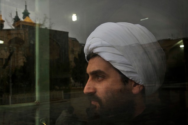 Homem olha por uma janela de uma sala de oração na universidade religiosa onde o Aiatolá Ruhollah Khomeini estudou, na cidade de Qom no Irã