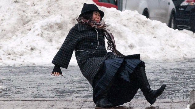 <p>A mulher cai ao escorregar no gelo durante uma chuva em Roosevelt Island, bairro de Manhattan, em Nova York</p>