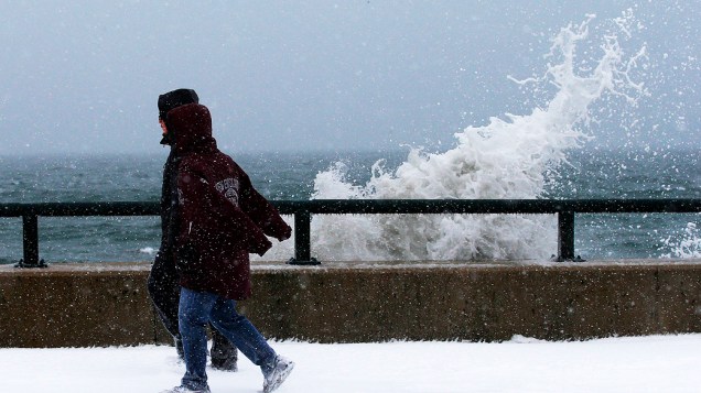 <p>Pessoas observam ondas batendo contra uma parede durante uma tempestade de neve em Massachusetts, nos Estados Unidos</p>