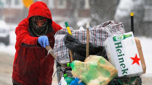 <p>Homem empurra um carrinho até a estrada durante uma tempestade de neve em Lynn, Massachusetts</p>