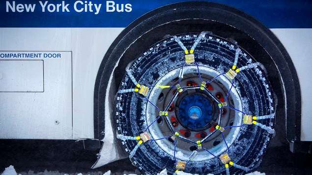 <p>Um ônibus com correntes em seus pneus enquanto dirige pela Quinta Avenida coberta de neve, em Nova York</p>