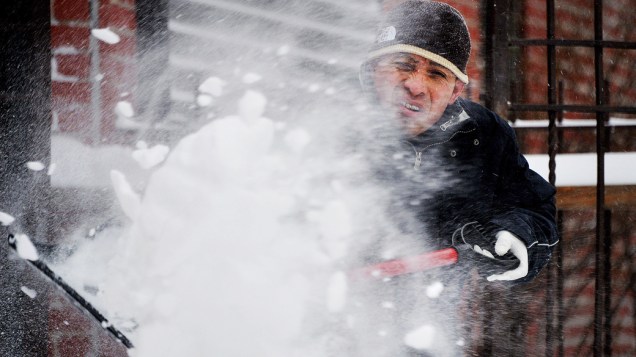 <p>Homem remove a neve da varanda de sua casa, no bairro de Brooklyn, em Nova York</p>