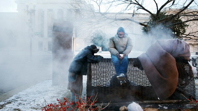 <p>Moradores de rua se aquecem em uma grelha de vapor do edifício da Comissão Federal de Comércio, nos arredores do Capitólio, em Washington</p>