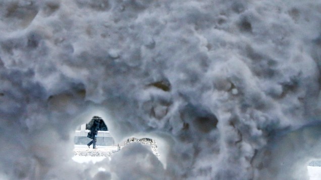 <p>Pessoa vista através da neve que cobriu um ponto de ônibus no centro de Chicago, Illinois</p>