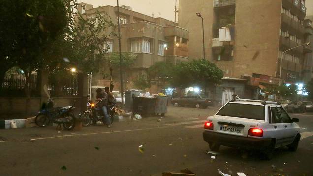 Motociclista se protege da tempestade de areia que atingiu Teerã, capital do Irã