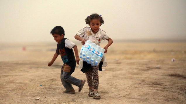 Crianças refugiadas da violência em Mosul, carregam água em um dos acampamentos nos arredores de Erbil, na região do Curdistão do Iraque