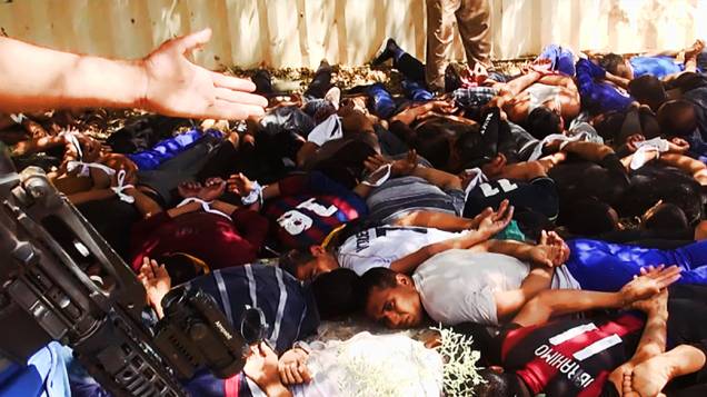 Imagem divulgada pelo site jihadista Welayat Salahuddin mostra militantes do Estado Islâmico do Iraque e do Levante (EIIL) ao lado de dezenas de iraquianos membros das forças de segurança  antes de serem executados em um local desconhecido