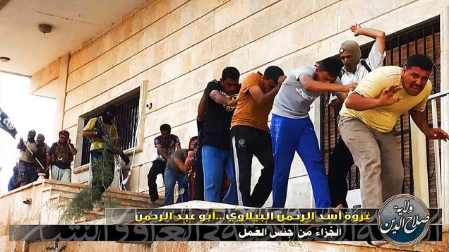 Imagem divulgada pelo site jihadista Welayat Salahuddin mostra militantes do Estado Islâmico do Iraque e do Levante (EIIL) ao lado de dezenas de iraquianos membros das forças de segurança antes de serem executados em um local desconhecido
