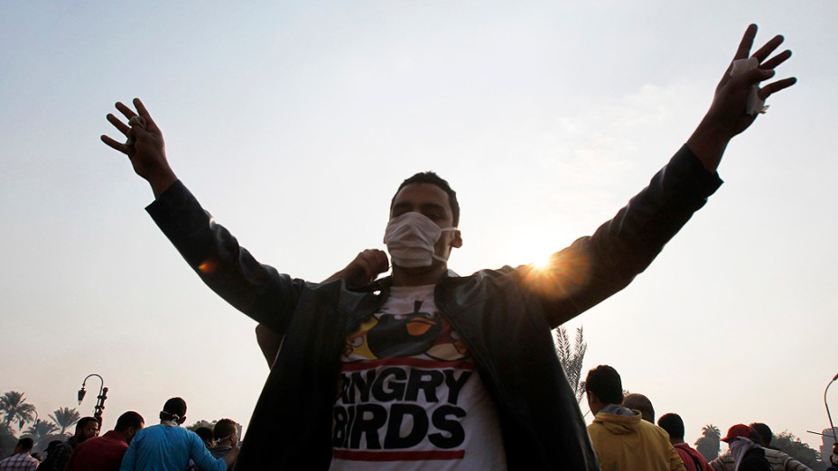 Membro da Irmandade Muçulmana aponta o número quatro, na frente da polícia de choque ao longo de uma estrada em Kornish El Nile, que leva à Praça Tahrir, durante os confrontos com a polícia, no Egito (06/10/2013)