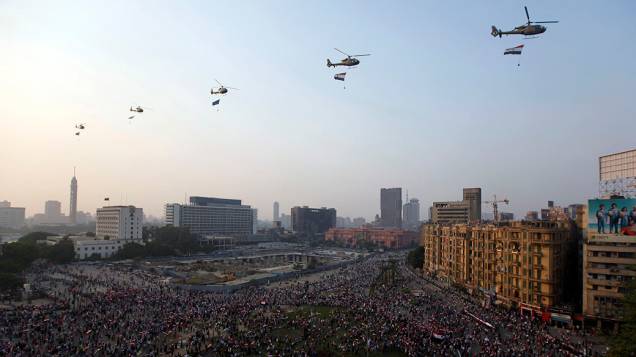 Helicópteros militares são vistos sobrevoando enquanto as pessoas se reúnem na Praça Tahrir para comemorar o aniversário de um ataque contra as forças israelenses durante a guerra de 1973, no Cairo (06/10/2013)