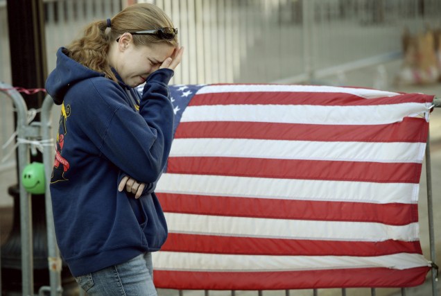 Jillian Blenis, cidadã de Boston, chora em frente a uma bandeira americana colocada na Boylston Avenue, em Massachusetts, Estados Unidos