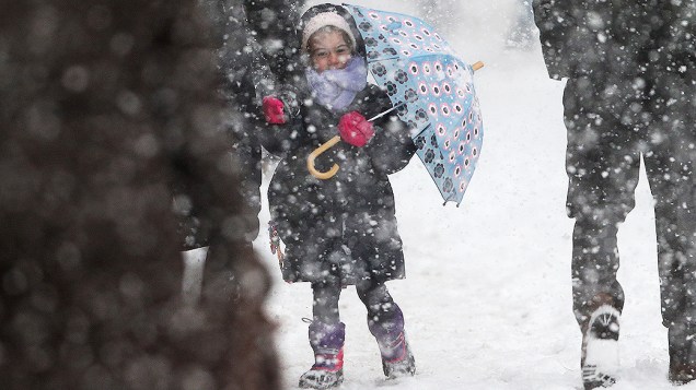 <p>Menina usa um guarda-chuva no caminho para a escola durante uma tempestade de neve em Nova York</p>