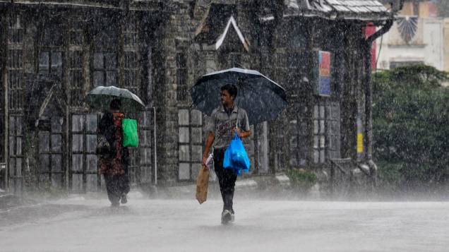 Pedestres caminham sob chuva forte na cidade de Shimla . As chuvas de monção registraram níveis médios mais elevados na primeira semana da estação chuvosa de quatro meses