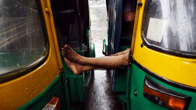 Homem descansa em seu riquixá durante um dia de chuva em Nova Délhi, Índia