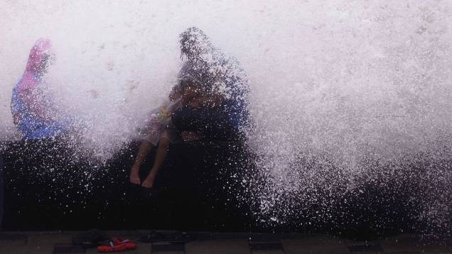 Crianças brincam aproveitando a maré alta em Worli Sea Face, na Índia