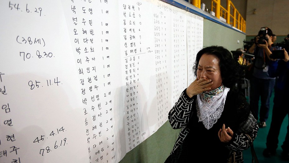 Mãe de um dos passageiros do navio que naufragou próximo a Jindo, na Coreia do Sul se emociona ao encontrar o nome do filho na lista de sobreviventes