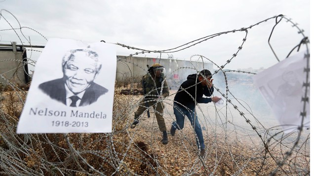 Cartaz com a imagem do ex-presidente sul-Africano Nelson Mandela fica preso sobre um arame farpado durante uma manifestação contra assentamentos judaicos na aldeia da Cisjordânia de Bilin, perto de Ramallah, na Palestina
