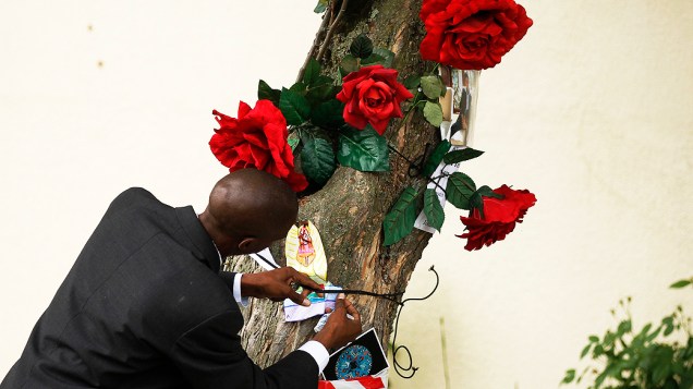 Homem coloca cartões em uma árvore do lado de fora da residência do ex-presidente sul-Africano Nelson Mandela, em Johannesburgo