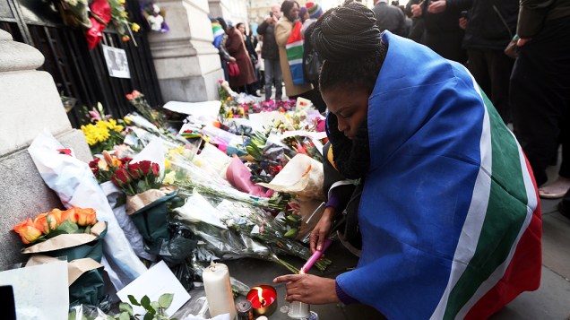 Mulher acende uma vela para prestar homenagem a Nelson Mandela em frente à embaixada sul-africana em Londres, na Inglaterra