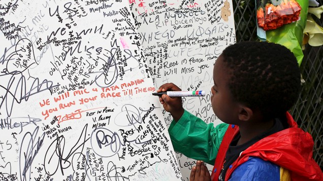 Menino escreve uma mensagem do lado de fora da residência do ex-presidente sul-africano Nelson Mandela, em Johannesburgo, África do Sul