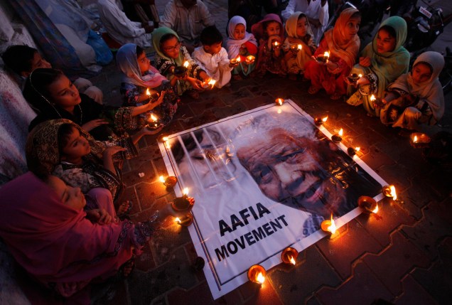 Crianças seguram lâmpadas de barro em homenagem ao ex-presidente sul-africano Nelson Mandela, organizada pelo Movimento Aafia, em Karachi, no Paquistão