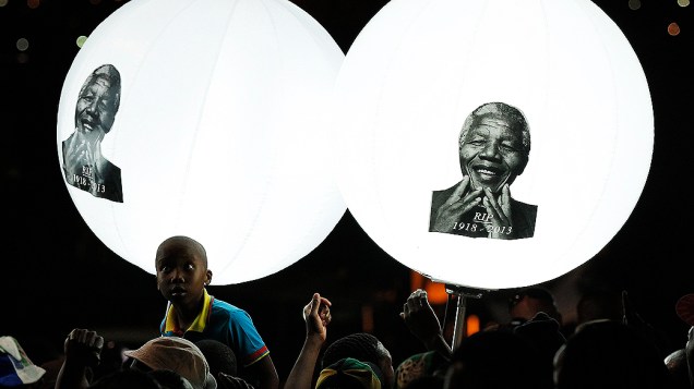 Menino olha para balões com a foto de Nelson Mandela em homenagem realizada ao ex-presidente da África do Sul em Vilakazi Street, no bairro de Soweto