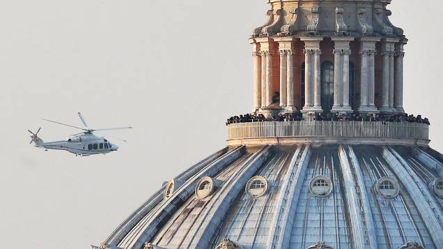 Pessoas lotam a galeria em cima da Basílica de São Pedro no momento em que o helicóptero que transportava o Papa Bento XVI passa em seu caminho