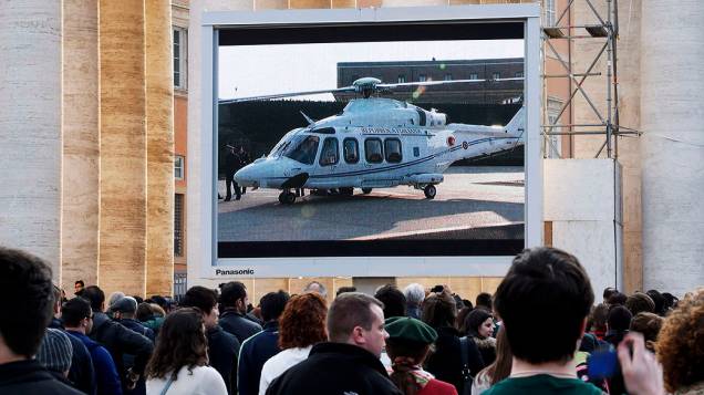 Fiéis assistem em um telão o helicóptero que levará o Bento XVI para a residência papal de verão, em Castelgandolfo
