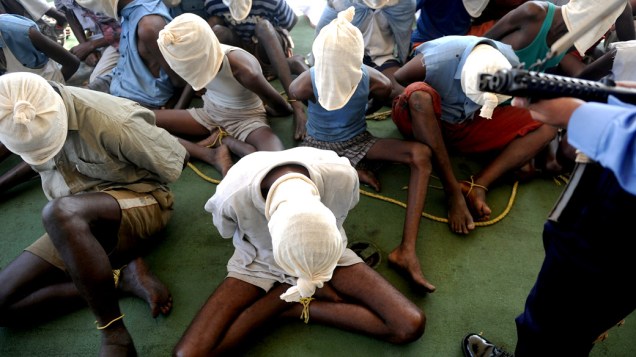 Piratas da Somália ficam com os rostos cobertos em um navio da guarda costeira indiana, após serem trazidos para Mumbai