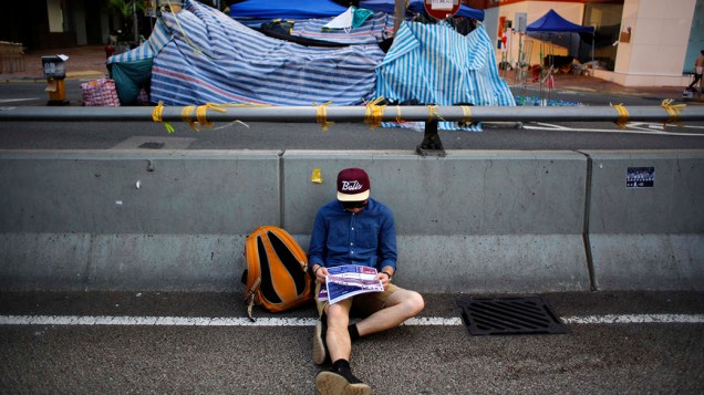 Um manifestante pró-democracia senta na rua em frente ao prédio do governo de Hong Kong