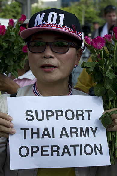 Na cidade de Bangcoc, ativista tailandesa segura um cartaz de apoio às forças militares que tomaram o poder depois de um golpe de Estado