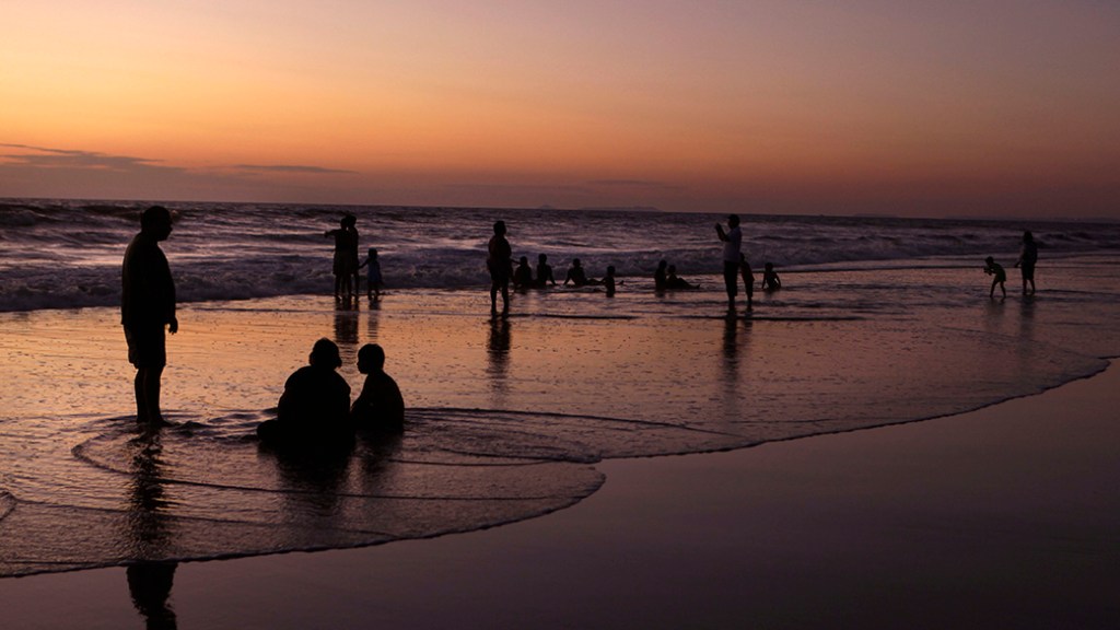 Pessoas são fotografadas durante o pôr-do-sol, na praia de Baga, na região de Goa, Índia
