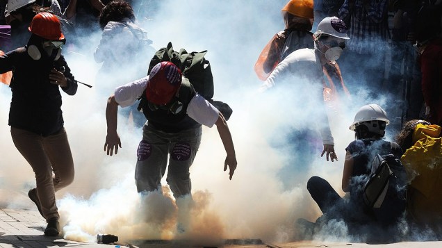Manifestantes correm em meio a bombas de gás lacrimogêneo disparado pela polícia durante os confrontos em Istambul, Turquia