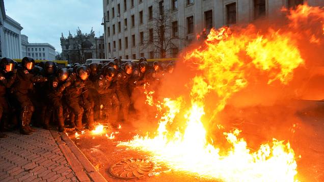 Um coquetel molotov explode em frente de membros da polícia de choque durante os confrontos com manifestantes, perto do escritório presidencial em Kiev, na Ucrânia