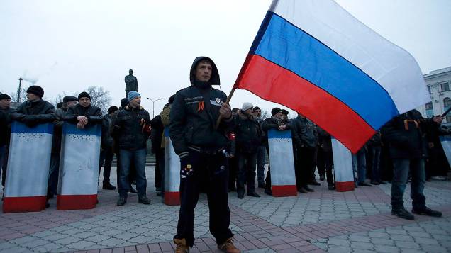 Homem segura a bandeira da Rússia durante um protesto em Crimeia, na Ucrânia em 01/03/2014