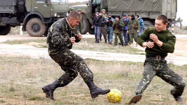 Soldados ucranianos jogam futebol próximo a veículos militares russos, na Crimeia