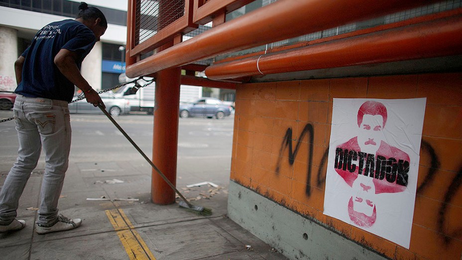 Cartaz do presidente da Venezuela, Nicolás Maduro, com a palavra Ditador é visto em um muro de Caracas, na Venezuela
