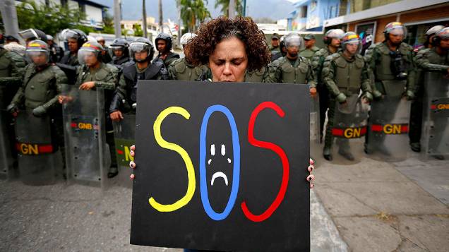 Manifestante segura um cartaz em frente a policiais da guarda nacional em frente a embaixada de Cuba em Caracas, na Venezuela - 25/02/2014