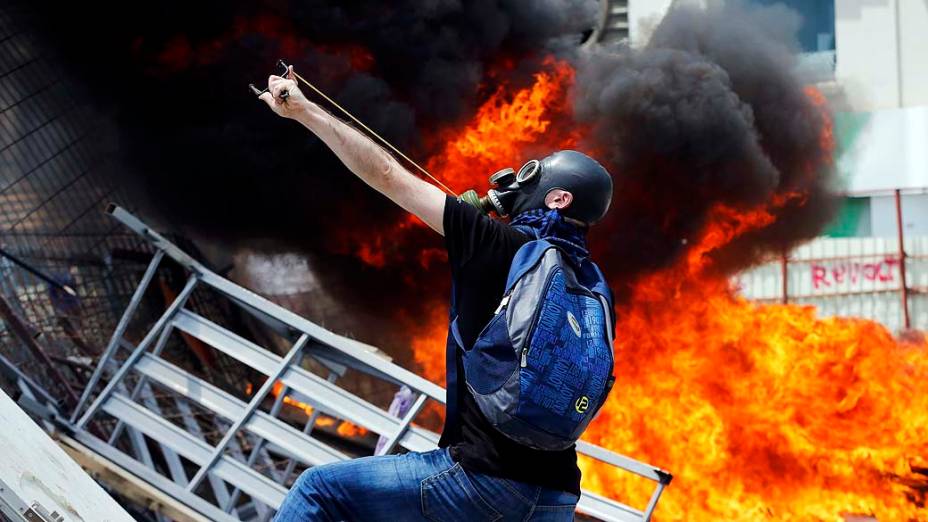 Manifestante usa um estilingue para atirar pedras contra a polícia de choque durante protesto na Praça Taksim, em Istambul