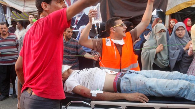 Partidários do presidente Mursi socorrem manifestante ferido durante confrontos com a polícia e opositores Mursi, em 27/07/2013