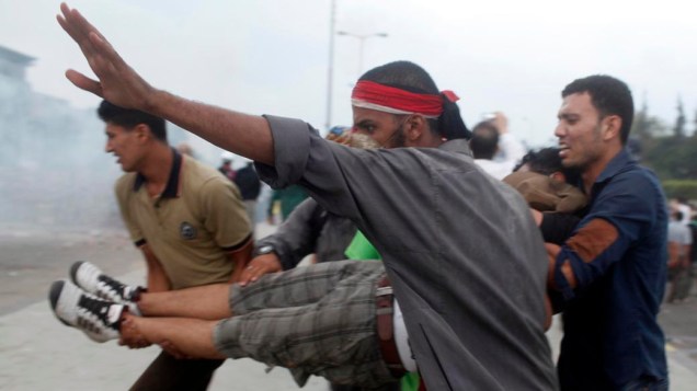 Partidários do presidente deposto Mursi carregam manifestante ferido durante confrontos com a polícia e opositores Mursi, na cidade de Nasr