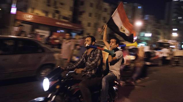 Homens em uma motocicleta carregam a bandeira egípcia durante um protesto pedindo a saída do presidente Mohamed Mursi, no Cairo, na segunda-feira 1º de julho