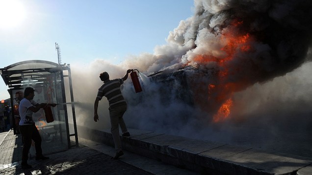 Homens tentam apagar incêndio em um carro de polícia na praça Taksim, em Istambul, durante os protestos contra o governo