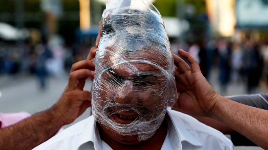Um manifestante cobre seu rosto com um filme plástico para se proteger das bombas de gás lacrimogêneo
