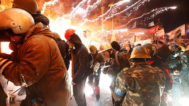 Fogos de artifício explodem perto de um grupo de manifestantes anti-governo durante confrontos com a polícia na Praça da Independência em Kiev