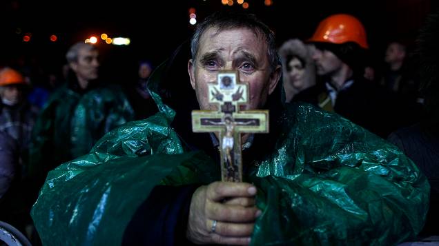 Manifestante anti-governo segura um crucifixo enquanto faz orações na Praça da Independência, em Kiev, na Ucrânia