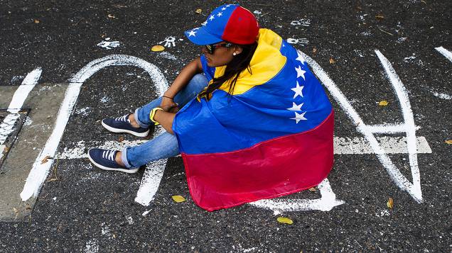 Manifestante com a bandeira da Venezuela em frente a um bloqueio de policiais durante protesto contra o governo do presidente Nicolas Maduro, em Caracas - (17/02/2014)