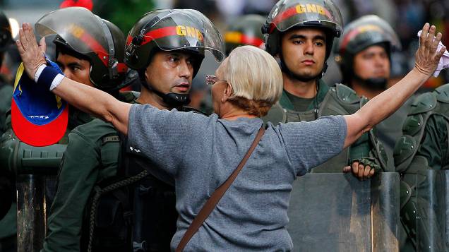 Manifestante da oposição se coloca em frente a uma barreira policial durante protesto contra o governo do presidente Nicolas Maduro, em Caracas