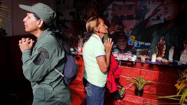 Uma militar e uma moradora do bairro de 23 de Enero, em Caracas fazem orações no aniversário de morte de Hugo Chávez